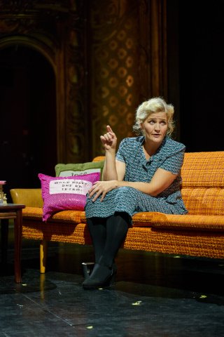 Kvinne i gul sofa på scene